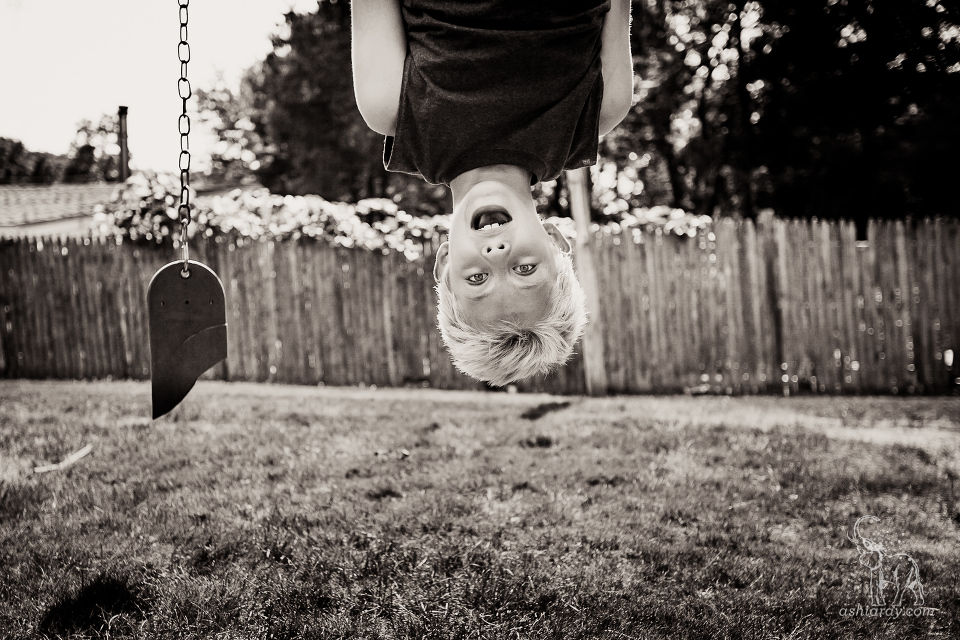 Boy hanging upside down from broken swingset
